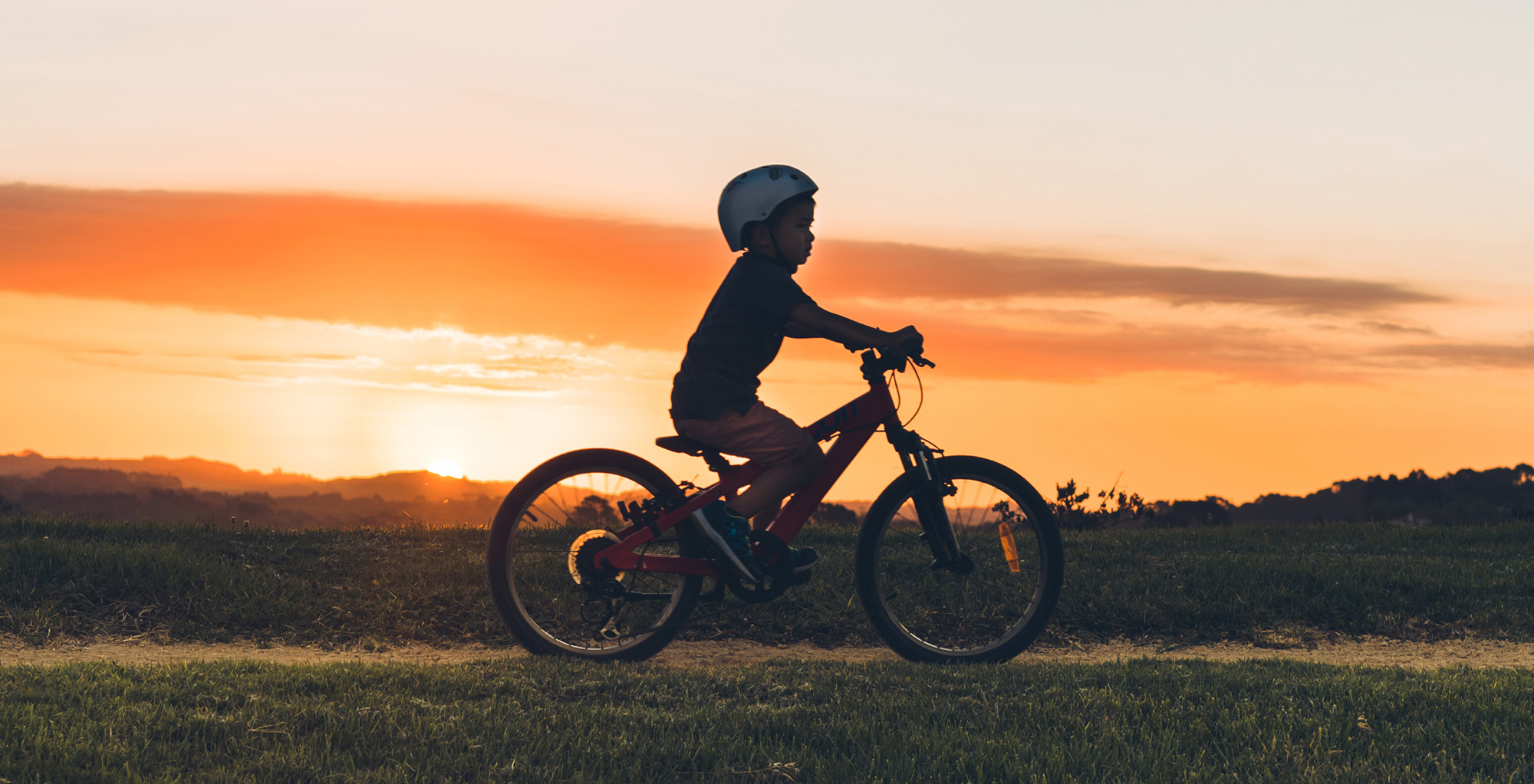 Boy riding a bike at sunset